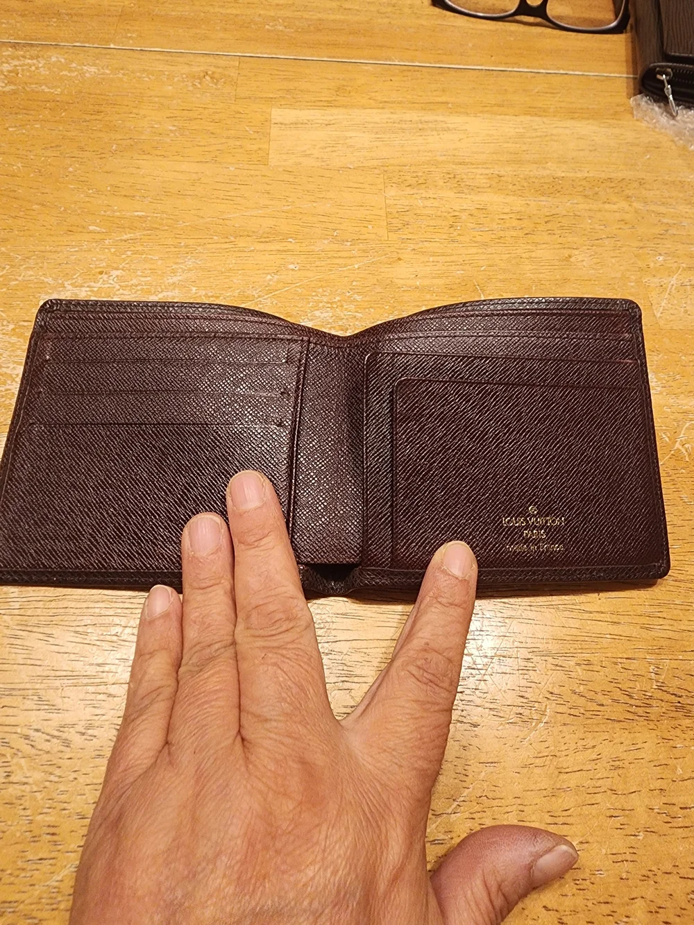 burgandy Louis Vuitton Taiga leather bifold wallet featuring a debossed LV